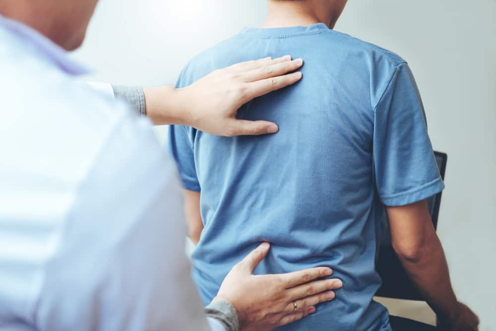 Chiropractor analyzing a man's spinal posture.